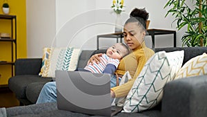 Mother and son sitting on sofa working while care baby at home