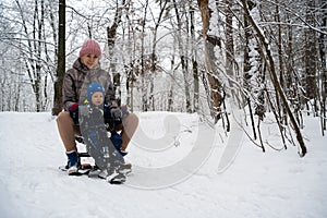 Mother and son sledding in the winter forest