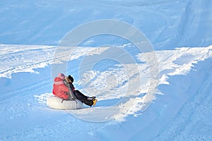 Mother and son sliding on snow tubing down the hill