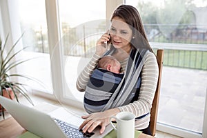 Mother with son in sling, with notebook and smartphone