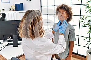 Mother and son smiling confident examining thoat at clinic