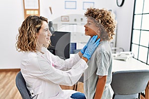 Mother and son smiling confident examining thoat at clinic