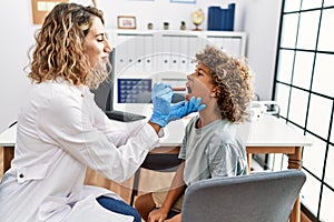 Mother and son smiling confident examining thoat at clinic