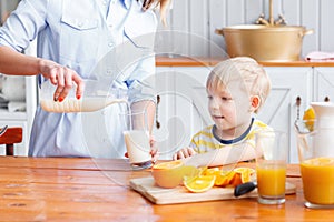 Mother and son are smiling while having a breakfast in kitchen. Mom is pouring milk into glass