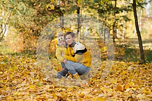 Mother And Son Smiling And Laughing in autumn park among yellow leaves