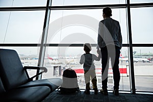 Mother and son standing near window in airport