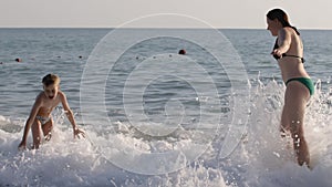 Mother and son are standing on the seashore and enjoying the surf. CREATIVE. Family on summer vacation swimming at the