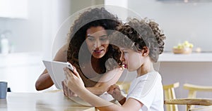 Mother and son with tablet playing games, talking and bonding while searching interactive education activity on tech