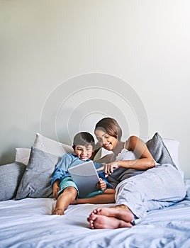 Mother and son time. Full length shot of an adorable little boy and his pregnant mother using a laptop while relaxing on