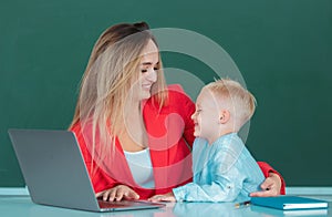 Mother and son together using computer laptop. Elementary school classroom. Teacher and schoolchild pupil in class