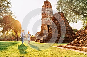 Mother and son tourists walking hand in hand in atcient Wat Chaiwatthanaram Buddhist temple ruines in holy city Ayutthaya, photo