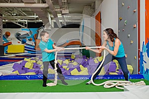 Mother and Son Tug of War in modern fitness center.