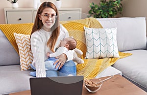 Mother and son using laptop breastfeeding baby at home