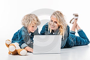 mother and son using laptop on floor