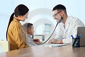 Mother and son visiting pediatrician in hospital. Doctor examining boy