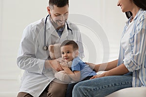 Mother and son visiting pediatrician in hospital. Doctor playing with boy