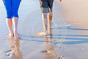 Mother and son walking along the beach. Legs.feet of the mother and the boy walk along the beach.Summer vacation