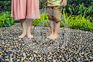 Mother and son Walking On A Textured Cobble Pavement, Reflexology. Pebble stones on the pavement for foot reflexology