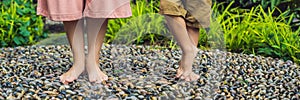 Mother and son Walking On A Textured Cobble Pavement, Reflexology. Pebble stones on the pavement for foot reflexology BANNER long