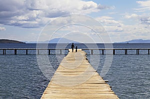 Mother and son walking on a wooden pier background with blue sky