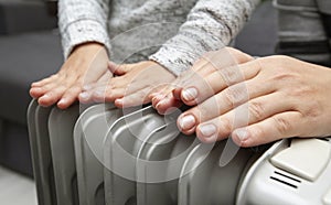 Mother and son warms hands above the electric radiator photo