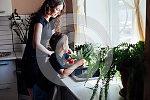 mother and son wash fresh vegetables with water in the kitchen