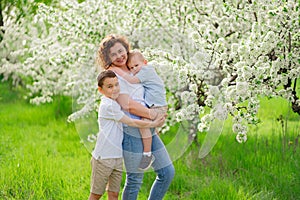 mother with sons in flowering garden. youngest child in her arms