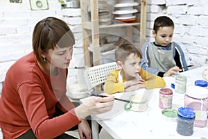 Mother with sons paint clay mugs