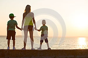 Mother and sons standing on the promenade and look at the river.