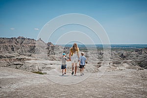 Mother and sons walking along a ridge, looking out at the rock formations of Badlands National Park