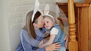 a mother soothes her crying daughter on the wooden stairs of the house.