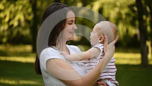 Mother soothing her baby son in summer park.