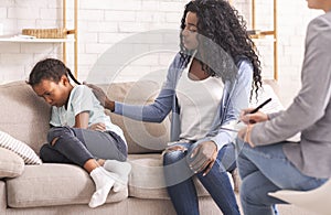 Mother soothing her upset disobedient little daughter at psychologist consultation