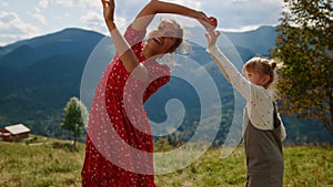 Mother spinning daughter dance summer holiday close up. Family dancing on nature