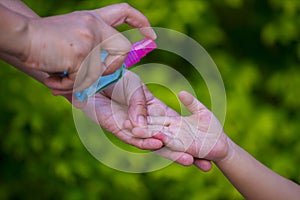 Mother spry alcohol to leaning her kids hand for  protect weak ill chemotherapy,  in Blure background