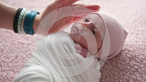 Mother Stroking Her Newborn Baby Girl In Wrapped In Swaddling Blankets