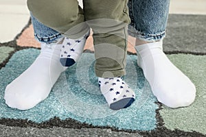 Mother supporting her son while he learning to walk on carpet, closeup