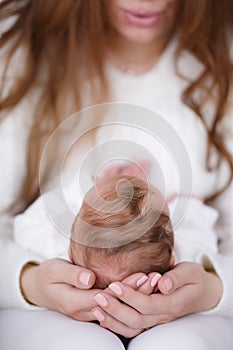 The mother supports the head of the baby lying on her lap