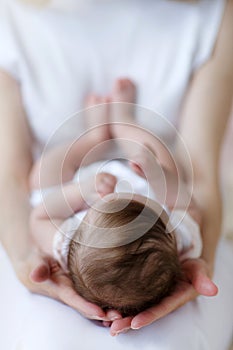 The mother supports the head of the baby lying on her lap