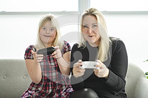 Mother and sweet down syndrome daughter girl at home play video game