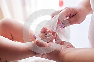 The mother takes care of the baby skin and wipes the baby`s feet with wet wipes photo