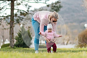 A mother takes care of her baby girl, who is learning to walk. Child development concept