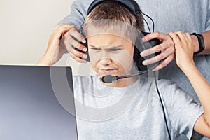 Mother takes off headphones her angry teenage son. Computer games addiction