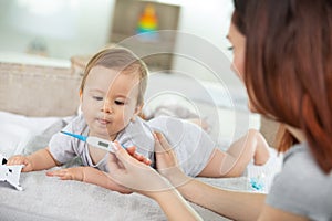mother taking babay temperature - illness concept