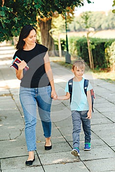 Mother taking child to school. First day at school. Parent and pupil of primary school go hand in hand