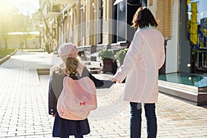 Mother taking child to school. Holding hands, background - autumn city.