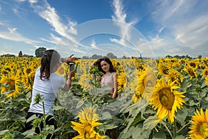 Mother taking photos of daughter in a field surrounded by sunflowers