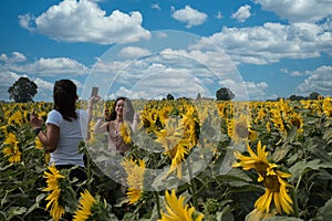 Mother taking photos of daughter in a field surrounded by sunflowers