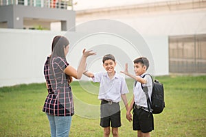 Mother taking sons to school together, hand wave say goodbye