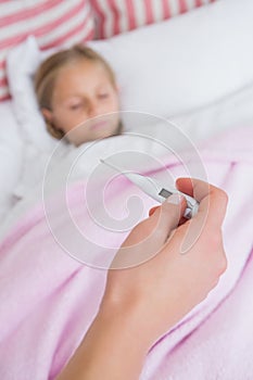 Mother taking the temperature of sick daughter